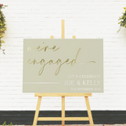 engagement party welcome sign with a sage background and gold lettering on a wooden easel stand